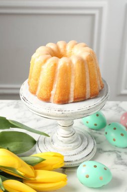 Lezzetli kek, Paskalya yumurtası ve laleler beyaz mermer masada, yakın plan.