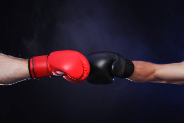 Boks eldivenli adamlar karanlık arka planda dumanla savaşıyor.