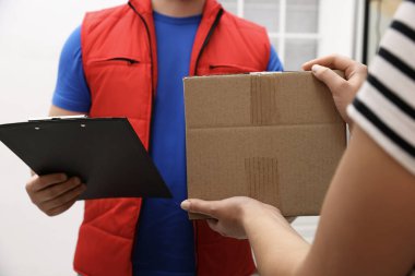 Elinde dosya olan kurye içerideki alıcıya paket veriyor, yakın plan.