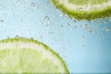 Açık mavi arka planda limon dilimli soda, yakın plan.