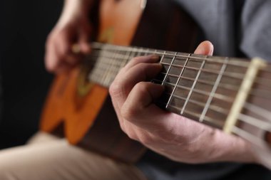 Siyah arka planda gitar çalan adam, ele odaklan.