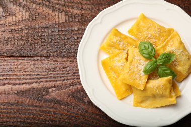 Ahşap masada parmesan peynirli ve fesleğenli nefis ravioli. Metin için boşluk