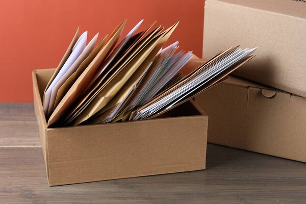 Различные бумажные конверты в коробке и посылки на деревянном столе. Почта