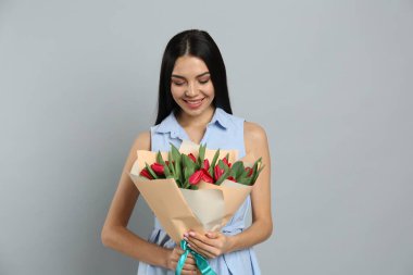 Açık gri arka planda kırmızı lale çiçekli mutlu kadın. 8 Mart kutlamaları