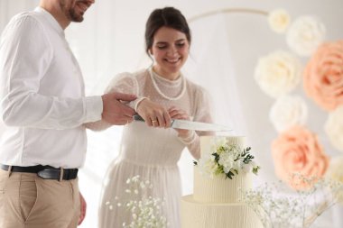 Evli çift evde bıçakla lezzetli bir düğün pastası kesiyor.