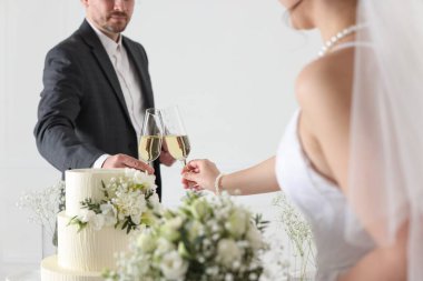 Mutlu evli çiftler şampanya bardakları tıkırdıyor. Düğün pastası içeride, yakın plan.