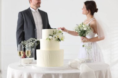 Evde evli bir çift, masadaki düğün pastasına odaklanıyor.