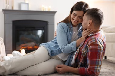 Mutlu çift evde şöminenin yanında vakit geçiriyor.