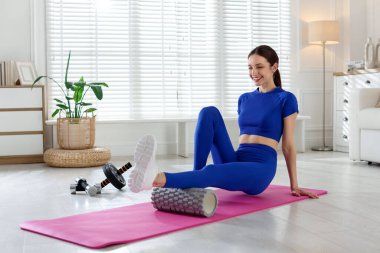 Mutlu kadın evde spor salonunda köpükle egzersiz yapıyor.