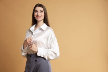 Bej arka planda şık giyinmiş güzel bir kadın. Metin için boşluk