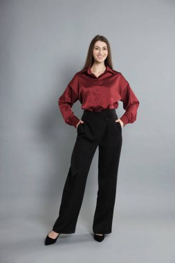 Gri arka planda şık giyinmiş güzel bir kadın.