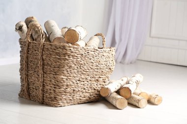 Beyaz zeminde kesilen odunlarla dolu bir sepet.