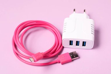 USB güç adaptörü ve kabloyu pembe arkaplanda şarj et, kapat