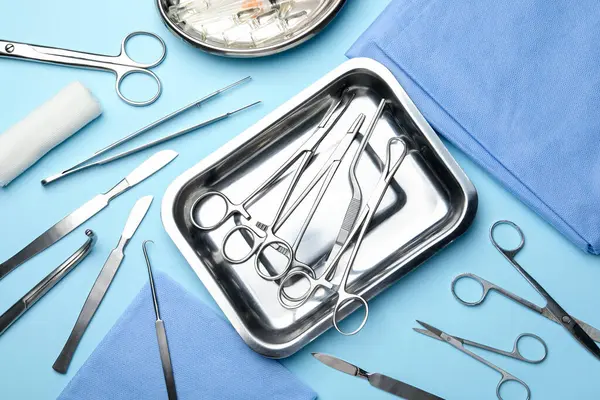 Açık mavi zemin üzerinde farklı cerrahi araçlar, düz yatıyordu