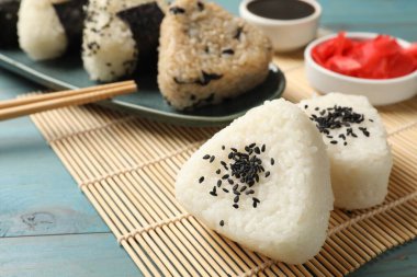 Pirinç topları (onigiri) açık mavi ahşap masada servis edilir. Geleneksel Japon yemeği