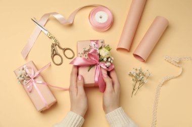 Çiçek kutuları, çiçekler, makas ve bej arka planda kurdele olan çiçekçi.