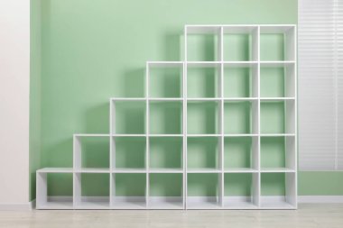 Empty shelving unit near olive wall indoors