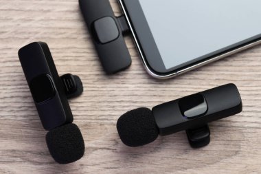 Lavalier mikrofonlar ve ahşap masada kablosuz alıcısı olan akıllı telefon.