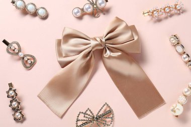 Farklı saç tokaları ve soluk pembe arka planda fiyonk.