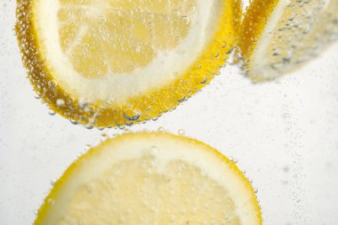 Arka planda limon dilimleri olan soda, yakın plan.