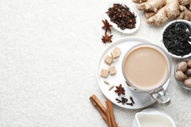 Beyaz desenli masa üzerinde, fincanda, baharatlarda, sütte ve esmer şekerde Aromatik Masala çayı, düz yatak. Metin için boşluk