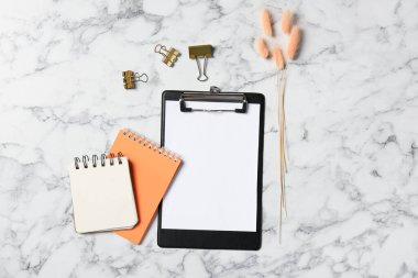 Boş kağıt, not defterleri, kuru çiviler ve beyaz mermer masa üzerindeki cilt raptiyeler, düz yatıyordu.