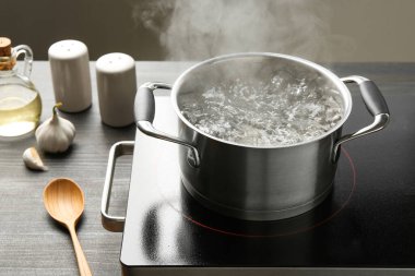 Kaynar suyla pişirme tenceresi ve ahşap masa üzerinde gri arka plan, yakın çekim