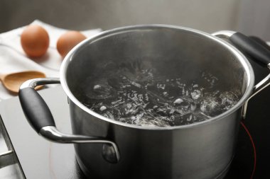 Kaynar suyla pişirme tenceresi ve soba gri arka planda, yakın plan