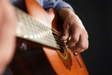Siyah arka planda gitar çalan adam, ele odaklan.