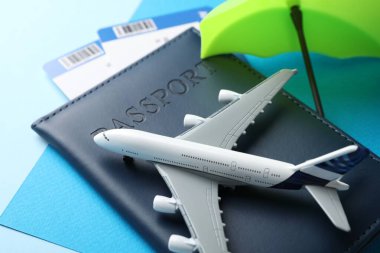 Seyahat sigortası. Uçak modeli, pasaport, küçük şemsiye ve açık mavi arka planda biletler, yakın plan.