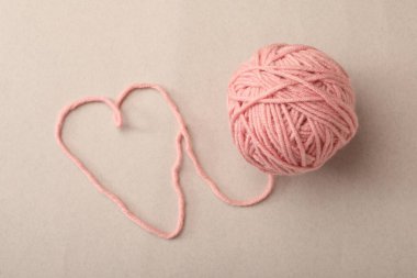 Gri arka planda yün iplikten yapılmış kalp, üst görünüm