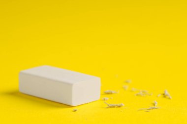 Sarı arka planda bir silgi ve kırıntılar, yakın plan. Metin için boşluk