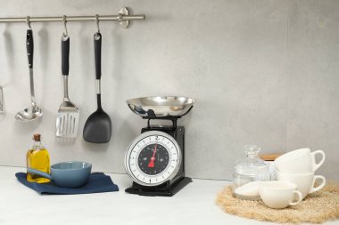 Retro mechanical kitchen scale and other utensils on white countertop indoors