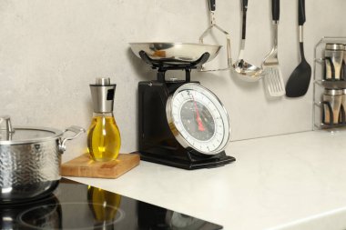 Beyaz mermer tezgah ve içerideki diğer aletler üzerinde retromekanik mutfak terazisi.