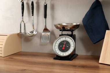 Retro mechanical kitchen scale on wooden countertop and other utensils indoors