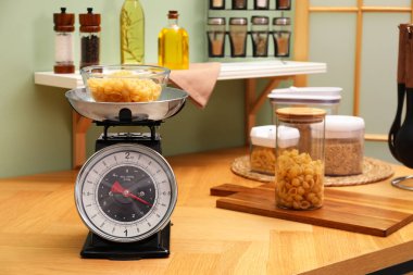 Kitchen scale, products and cooking utensils on wooden table