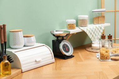 Kitchen scale, products and cooking utensils on wooden table