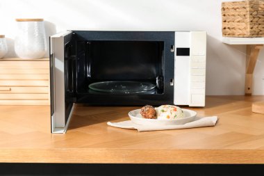 Mikrodalga fırını aç, pilav ve tavukla birlikte ahşap masa içinde.