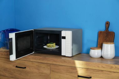 Mikrodalga fırını lazanya ve mutfak gereçleri ile aç.