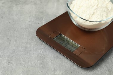 Modern elektronik mutfak terazisi ve gri masa üzerinde bir kase un, yakın plan. Metin için boşluk