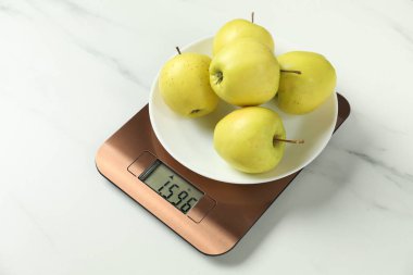 Modern elektronik mutfak terazisi, beyaz mermer masa üzerinde elmalar, yakın çekim