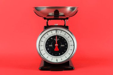 Mechanical kitchen scale with bowl on red background