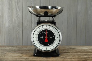 Mechanical kitchen scale with bowl on wooden table