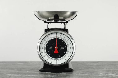 Mutfak terazisi. Koyu renkli tabakta gri arka planda.