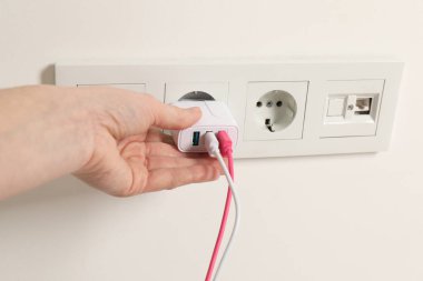 USB adaptörünü kablolarla elektrik prizine bağlayan kadın, yakın plan