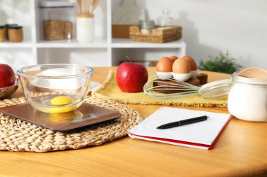 Elektronik mutfak ölçeği, ürünler ve ahşap masa üzerindeki kırtasiye.