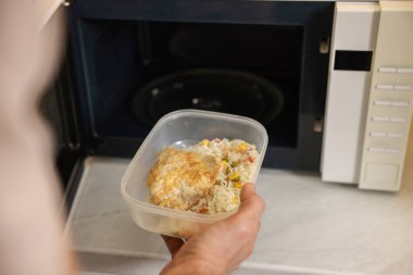 Yemek kabını mikrodalgaya koyan adam, yakın plan.