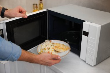 Yemek tabağını mikrodalgaya koyan adam, yakın plan.