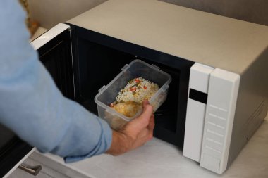 Yemek kabını mikrodalgaya koyan adam, yakın plan.