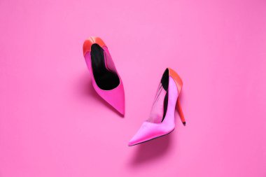Pembe arka planda bir çift yüksek topuklu ayakkabı.